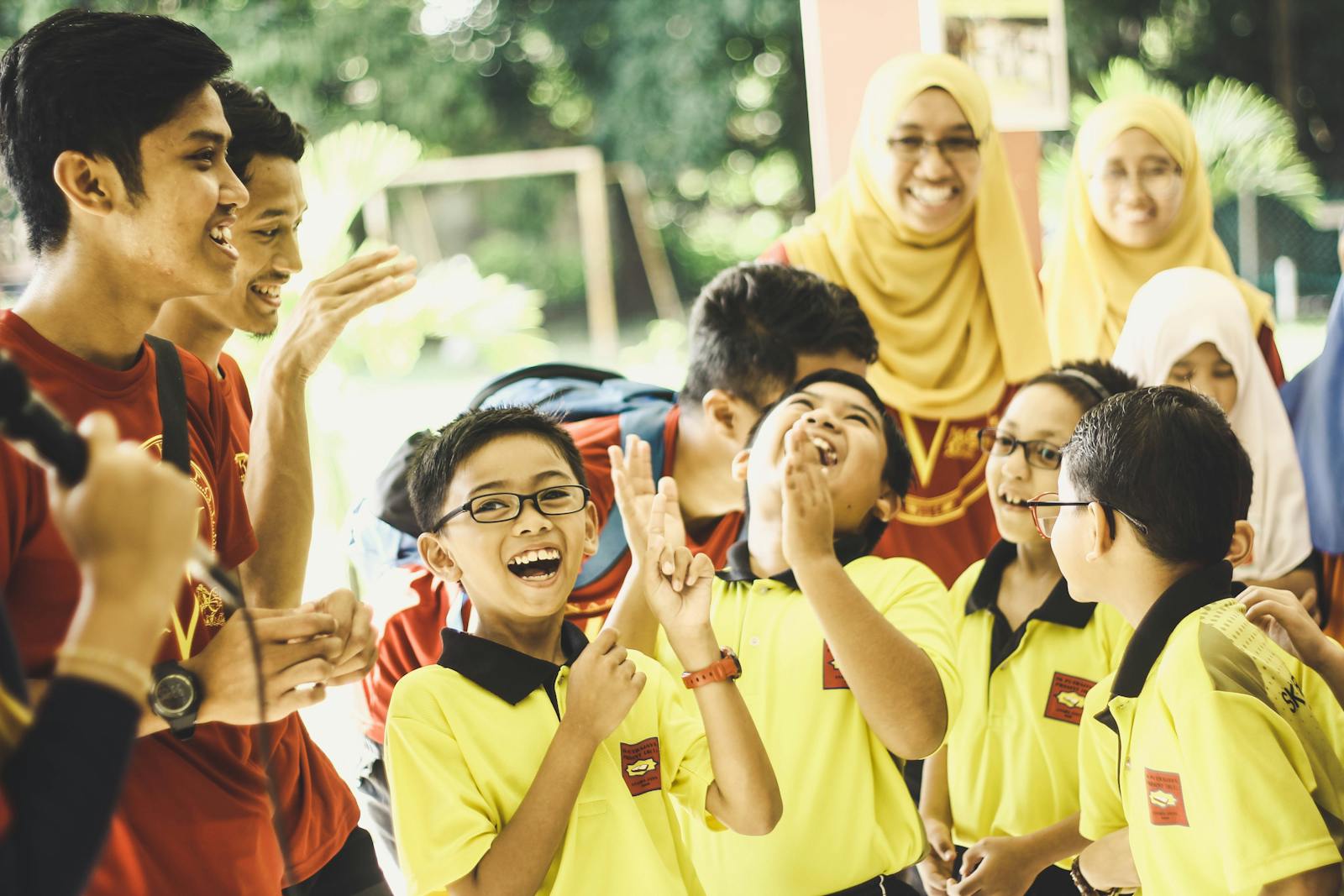 A group of school children enjoying a celebratory outdoor event with teachers in Pahang, Malaysia.