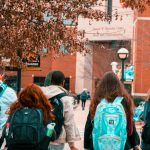 A group of college students with backpacks walking together outdoors on campus.