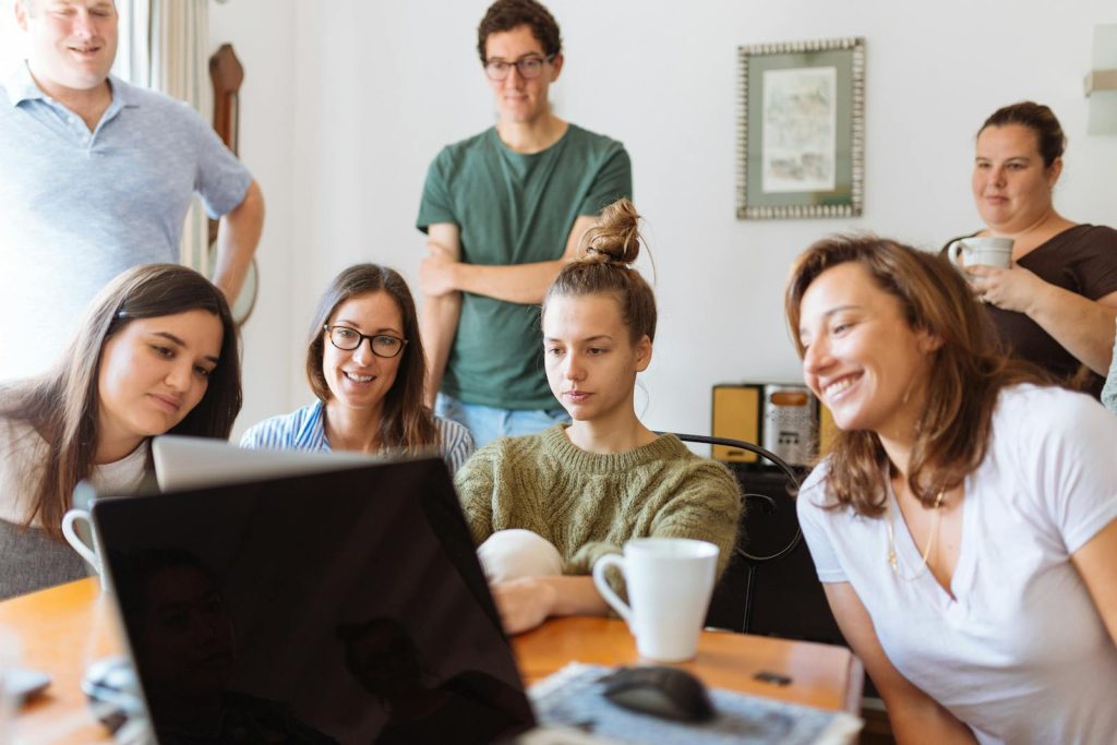 A diverse group of adults at work, enjoying a casual meeting indoors with focus and smiles.