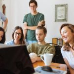 A diverse group of adults at work, enjoying a casual meeting indoors with focus and smiles.