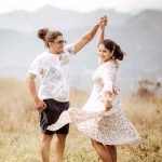 A joyful couple enjoying a dance in a sunlit meadow, showcasing love and happiness.