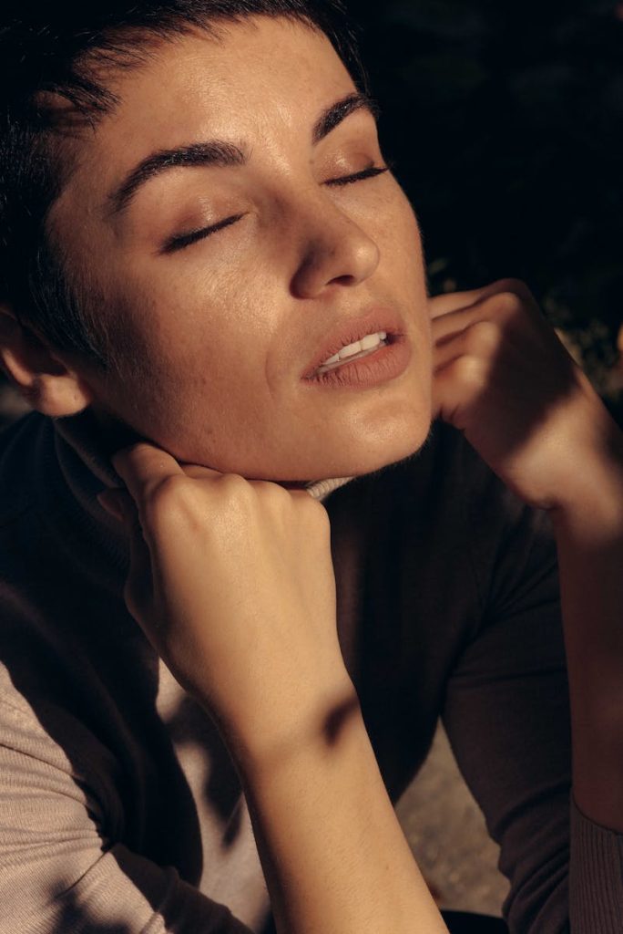 A serene portrait of a woman with closed eyes, basking in warm sunset light, conveying tranquility.