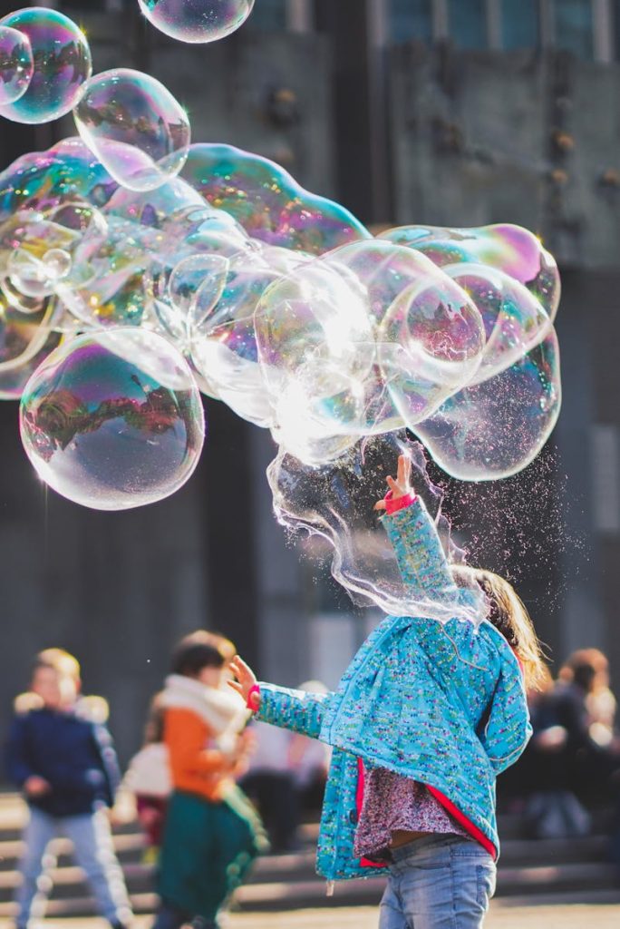 A child delights in chasing and popping giant bubbles in an outdoor setting.