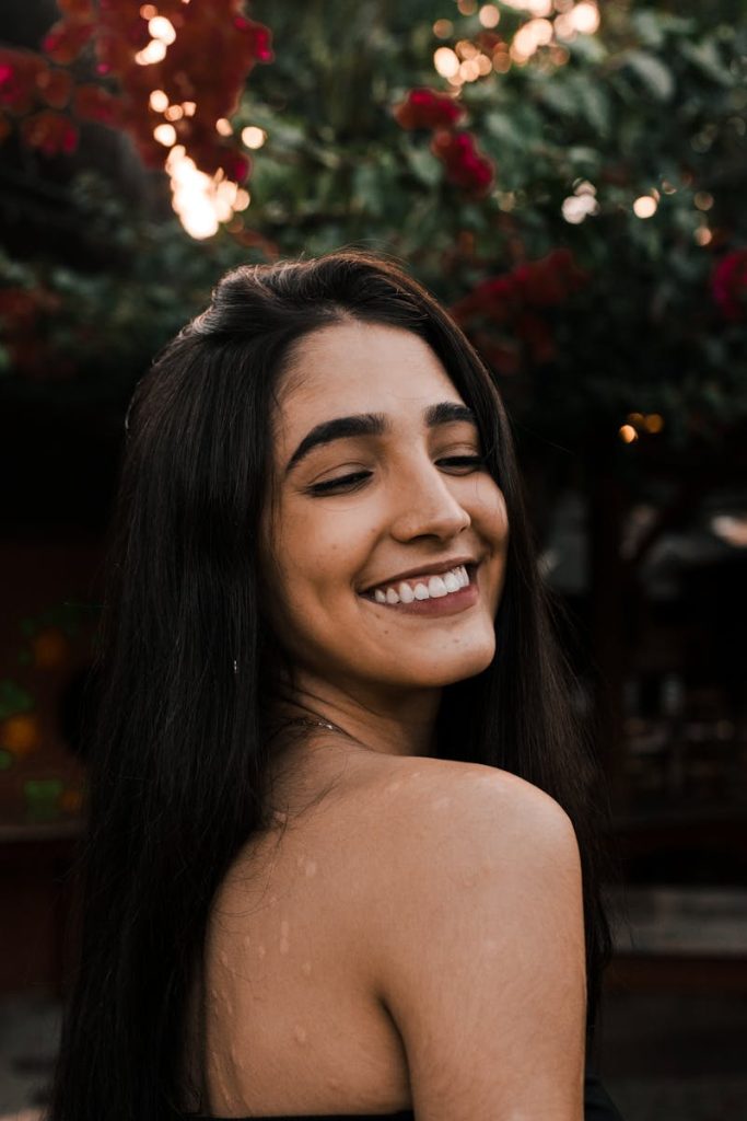 A woman enjoying a serene moment outdoors amidst soft lighting and foliage.