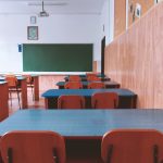 A tranquil empty classroom with wooden furniture and a green chalkboard, perfect for educational themes.