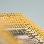 Detailed close-up of gold CPU pins, showcasing technology and design on a circuit board.