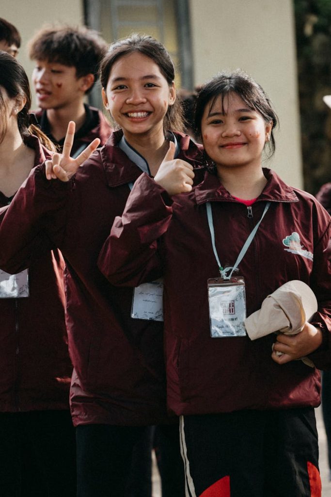 Smiling teenagers in maroon jackets posing outdoors, expressing joy and togetherness.