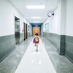 A child runs through a bright school hallway, emphasizing modern architecture and energy.