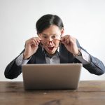 Surprised man in a suit looking at laptop, expressing disbelief indoors.