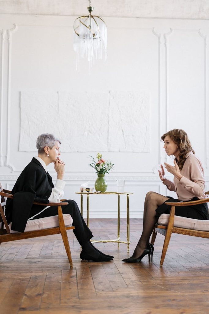 Two women engaged in a counseling session in a bright, modern loft setting.