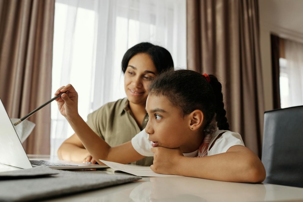 Mother and daughter engaged in online learning at home, using a laptop.