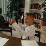 Boy engaging in a science experiment with a magnifying glass and test tube in a library.