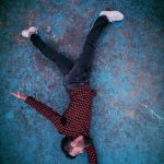 Overhead view of a man in a red checkered shirt lying on a textured blue background.