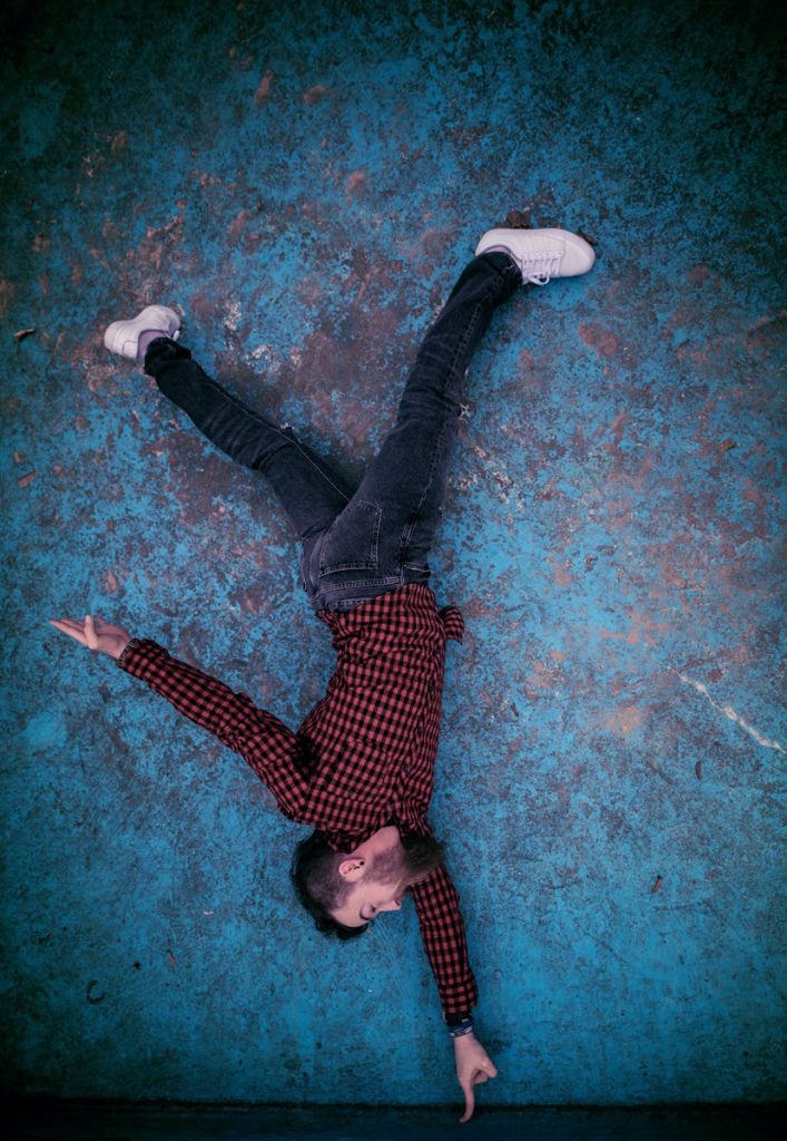 Overhead view of a man in a red checkered shirt lying on a textured blue background.