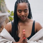 African American woman meditating outdoors with closed eyes, embracing serenity by the sea.