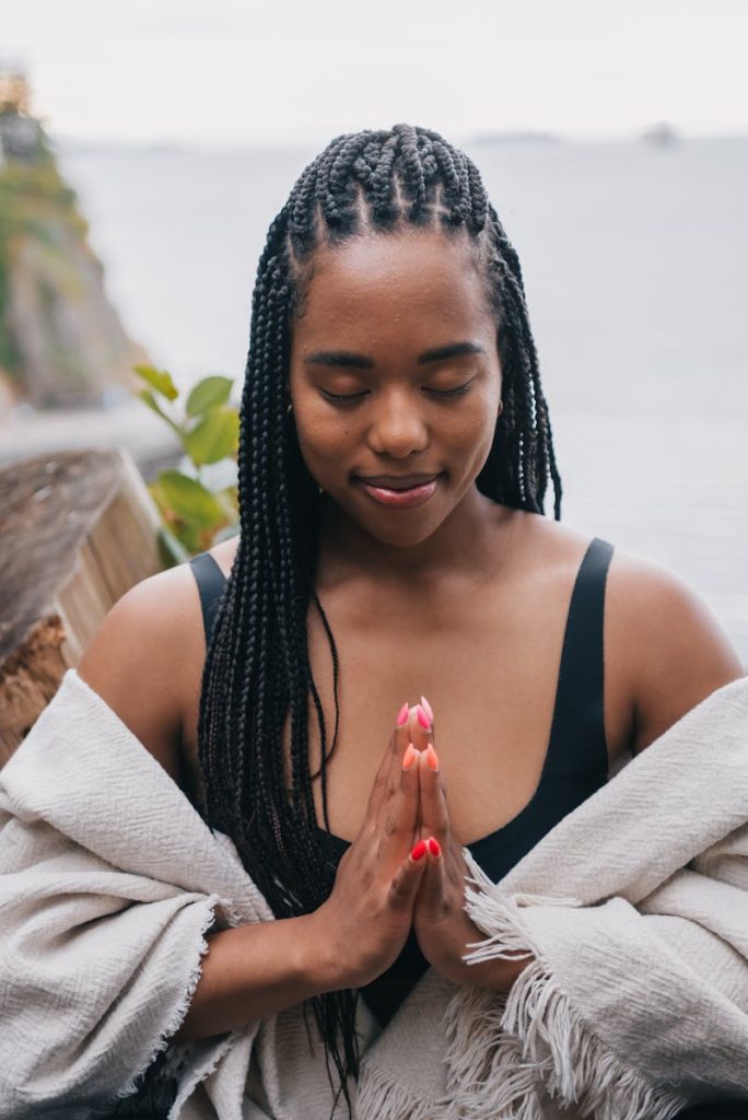 African American woman meditating outdoors with closed eyes, embracing serenity by the sea.