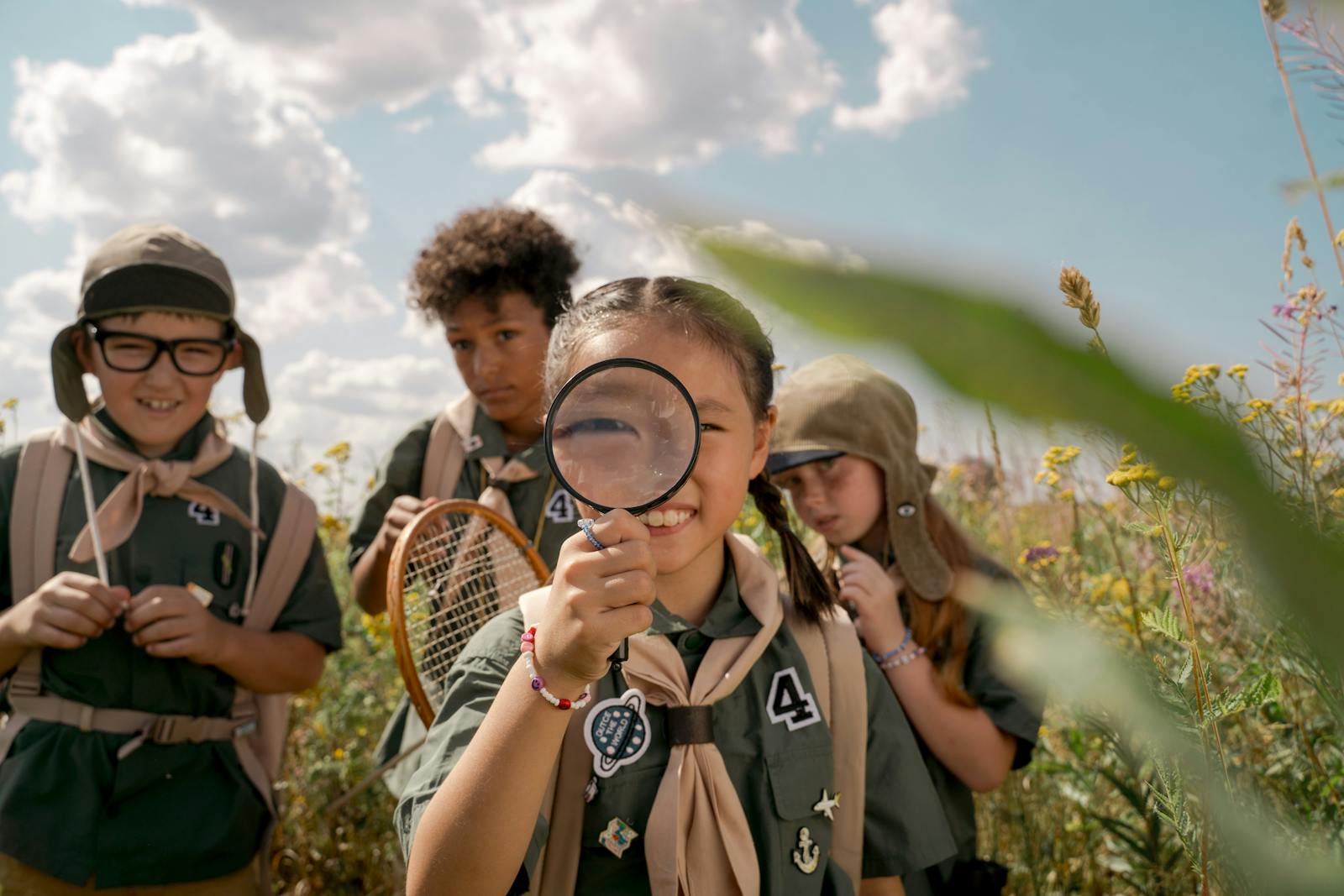 Group of children exploring the outdoors in scouting uniforms on a sunny day.