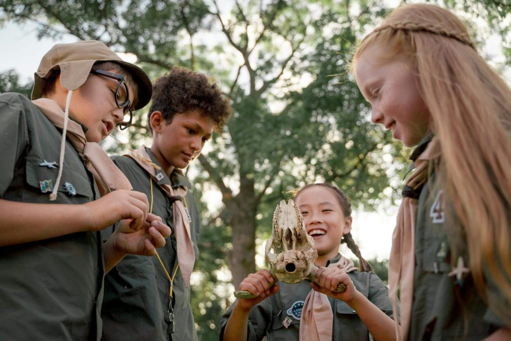 Group of scouts exploring nature, holding an animal skull in the forest.