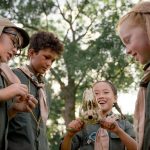 Group of scouts exploring nature, holding an animal skull in the forest.