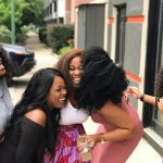 A joyful group of friends sharing a moment of laughter on a sunny day outdoors.